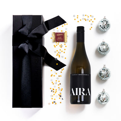 Wine bottle labeled 'AIRA' with a gift box and decorative items on a white background