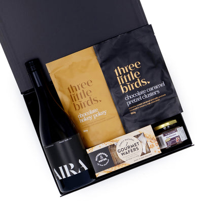 Gift set with 'three little birds' chocolate products and 'AIRA' wine bottle on a white background